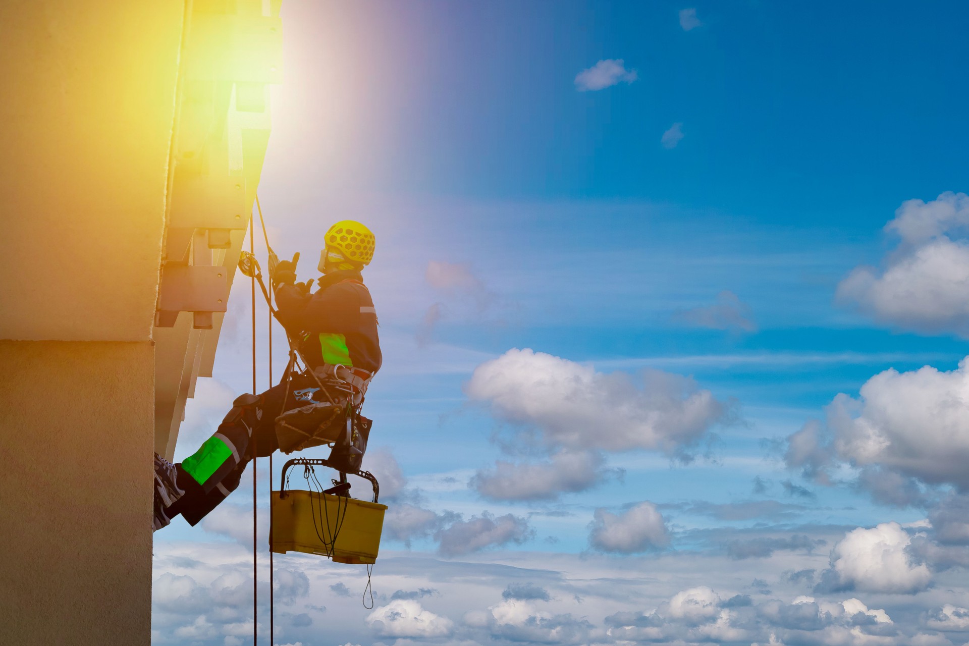 Industrial mountaineering worker in uniform washing exterior glazing